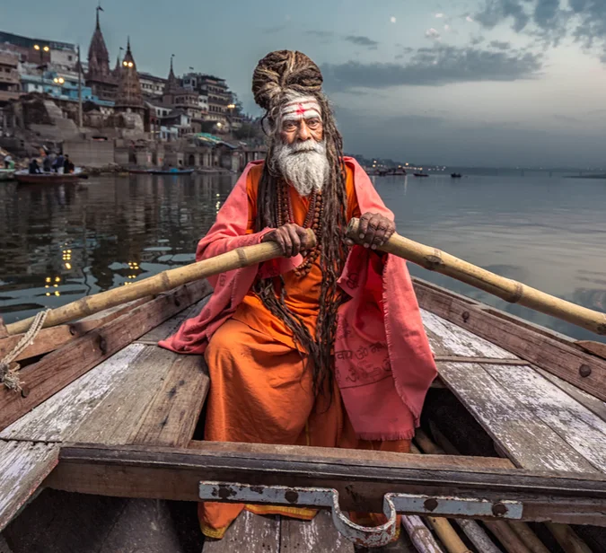 Sadhu fører robåt på Ganges i Varanasi – et hellig morgenbilde fra mange reiser til India.
